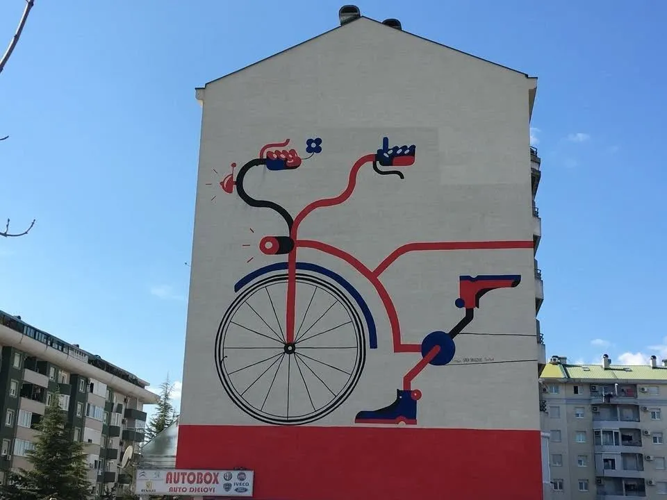 Fasada stambene zgrade sa velikim muralom bicikla.