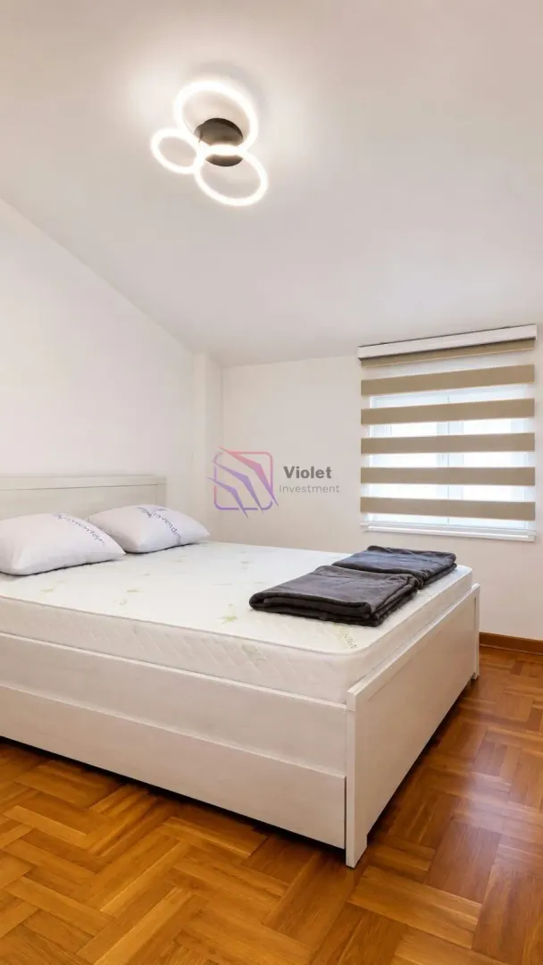 A bedroom with a double bed and hardwood flooring.