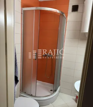 Small bathroom with a shower cabin and orange wall tiles. - image 7