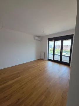 Prazna soba sa drvenim podom, klima uređajem i balkonskim vratima. - image 2