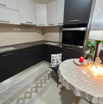 Kitchen with dark lower and light upper cabinets, dining table, and built-in oven. - image 4
