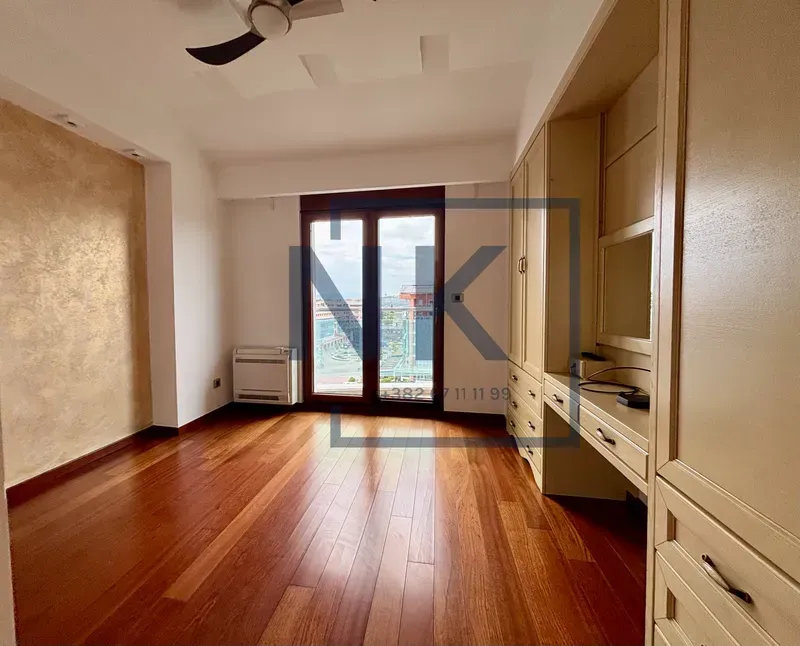 Bedroom with built-in wardrobes, a desk, and wooden flooring.