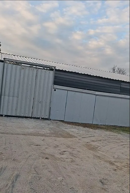 Exterior of a metal building with sliding gates and a tin roof.