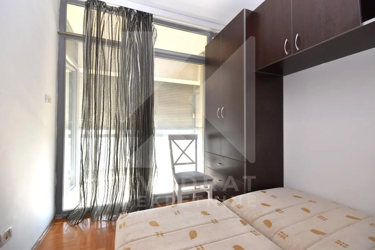 Furnished bedroom with a bed, built-in wardrobe, and balcony doors.