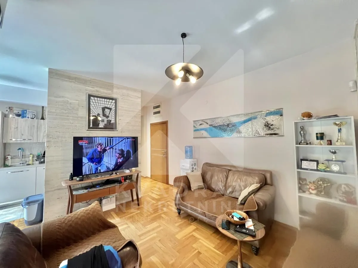 Living room with sofa, television, and bookshelves.