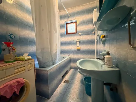 Kupatilo obloženo pločicama sa kadom, umivaonikom i veš mašinom. - image 12