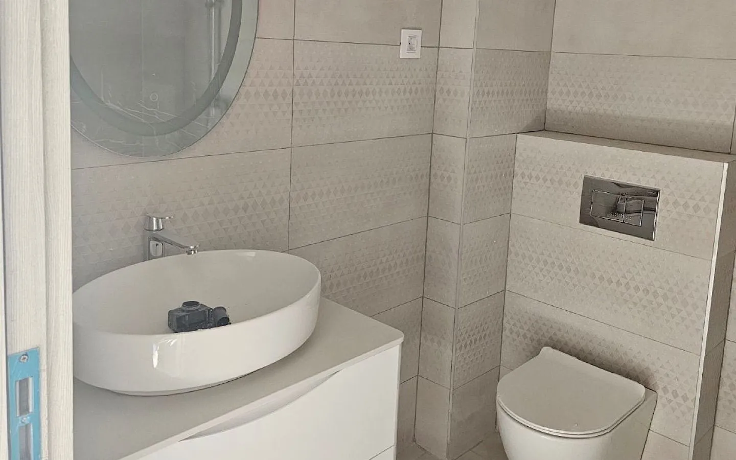 Moderne kupatilo sa umivaonikom i ugrađenom šoljom.