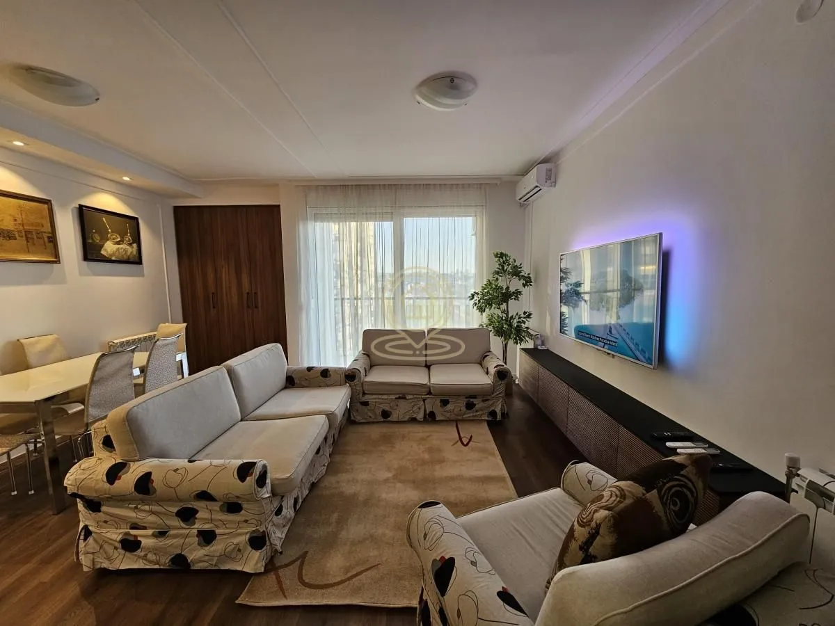 Living room with a seating area, TV and a dining area in the background.