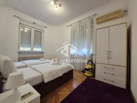 Bedroom with two single beds, wardrobe, and windows. - image 15