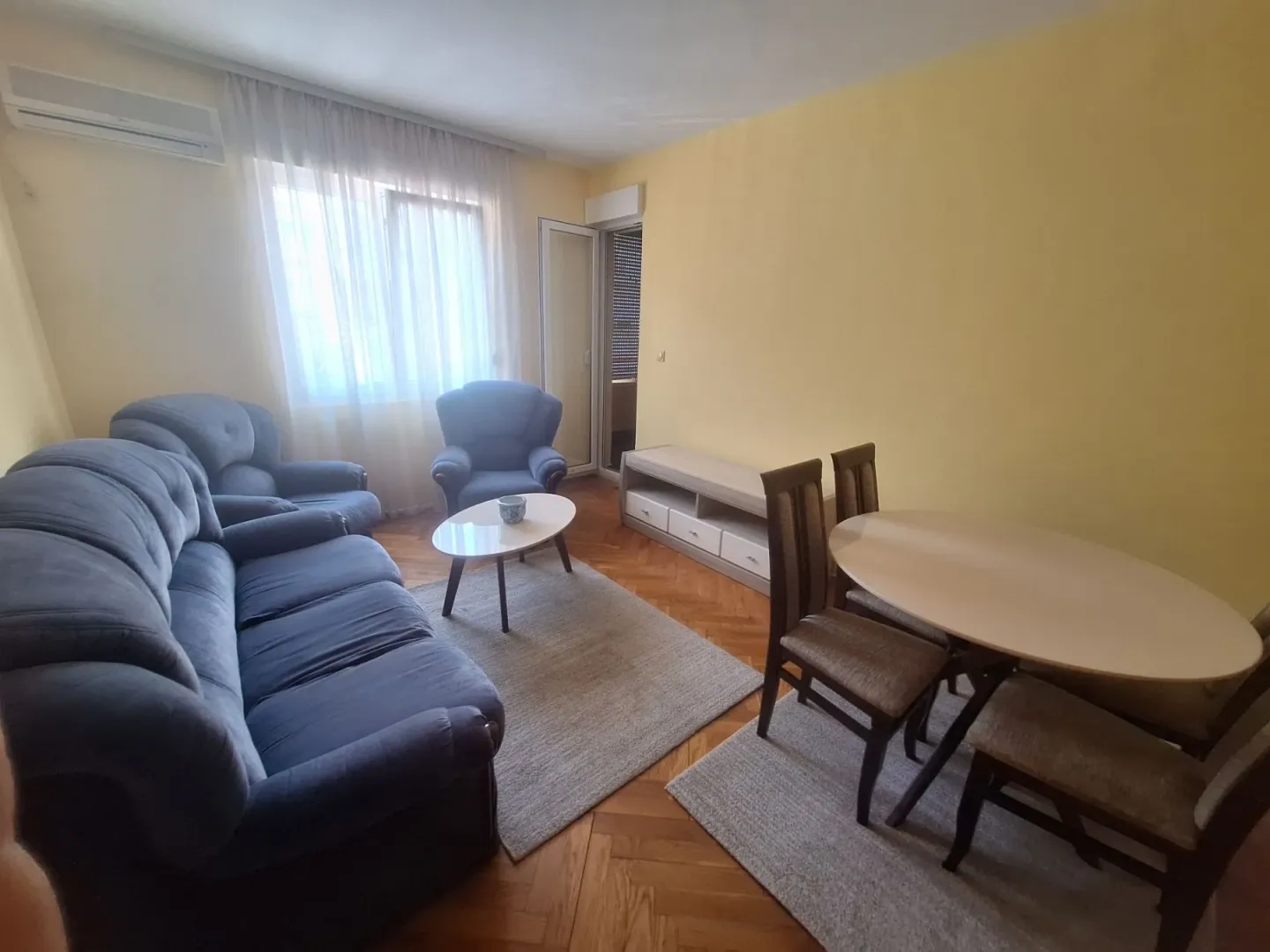 Dnevna soba sa garniturom, trpezarijskim stolom i izlazom na terasu.