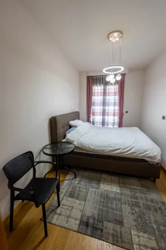 Bedroom with a double bed, small table, chair, and modern chandelier. - image 9
