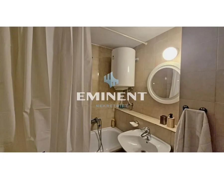 Bathroom equipped with a sink, bathtub with a curtain, and a water heater.