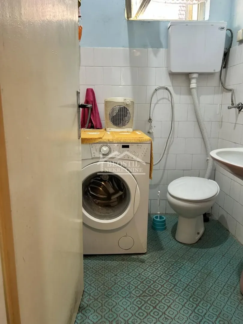 Manje kupatilo sa sanitarijama, umivaonikom i veš mašinom.
