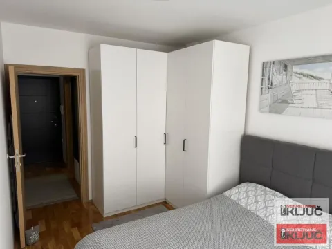 Nameštena spavaća soba sa bračnim krevetom, velikim belim plakarom i ulaznim vratima. - image 4