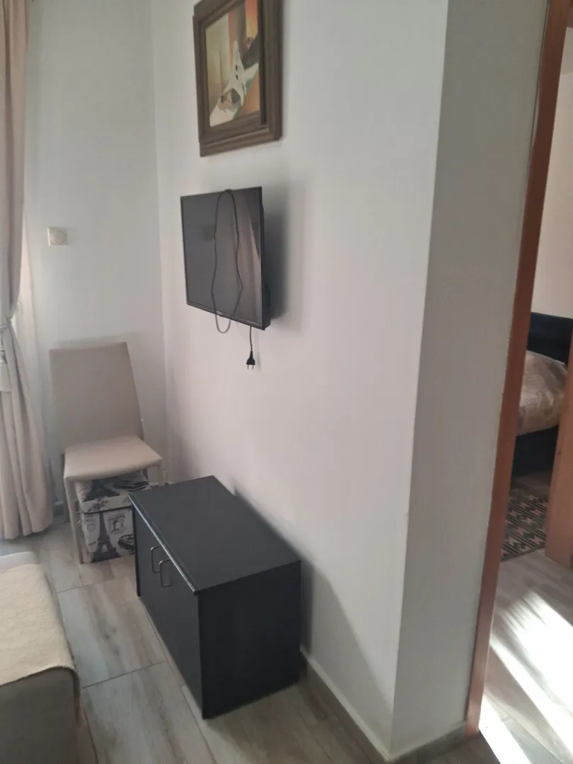Smaller living room with a wall-mounted TV and a chest of drawers.