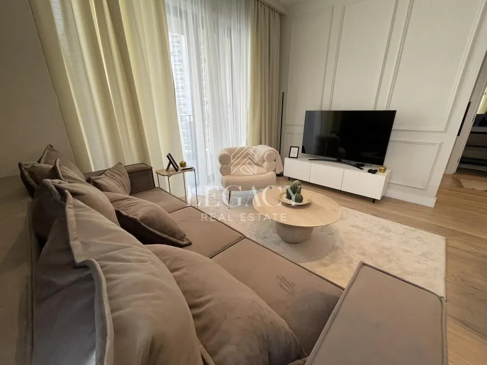 Moderan dnevni boravak sa garniturom, stočićem i televizorom.