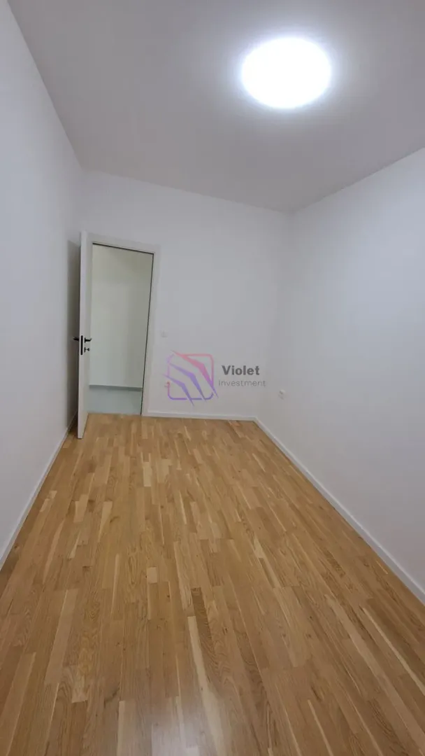 Empty room with parquet flooring and an open door.