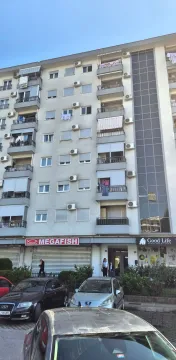 Spoljašnji izgled stambene zgrade sa poslovnim prostorima u prizemlju i parkiranim automobilima ispred. - image 5