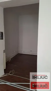 Prazna prostorija sa tamnim laminatom i belim zidovima. - image 18