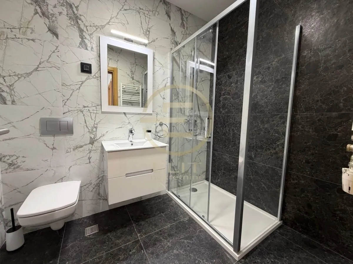 Moderno opremljeno kupatilo sa tuš kabinom, umivaonikom i WC šoljom.