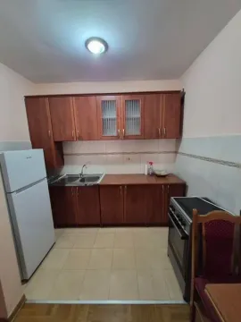 Small kitchen with wooden cabinets, a refrigerator, and a stove. - image 4