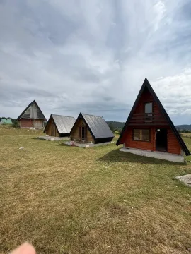 Pogled na drvene vikendice A-oblika na travnatom placu. - image 4