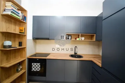 Modern kitchen with dark cabinets, wooden details, and bookshelves. - image 5