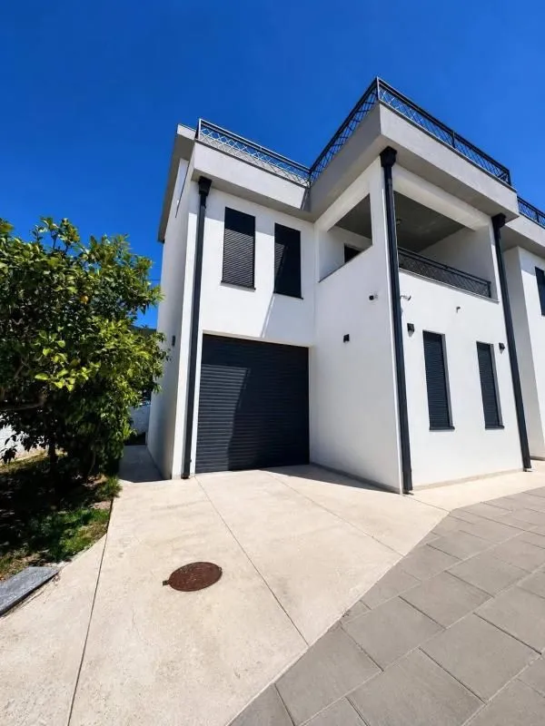 View of the exterior of a modern house with a garage and yard.