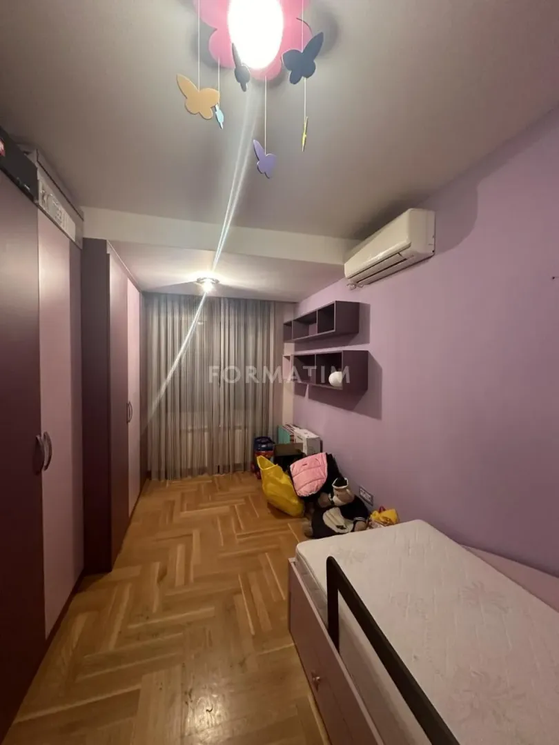 Children's bedroom with a bed, wardrobe, and parquet flooring.