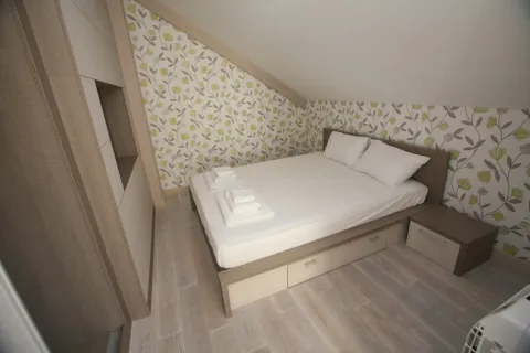 Furnished bedroom with a double bed under a sloped ceiling. - image 10