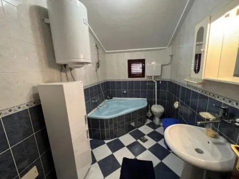 Bathroom with blue and white tiles, a corner bathtub, and a boiler. - image 24