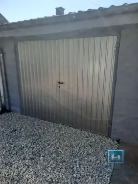 View of the garage door with gravel in the yard. - image 2
