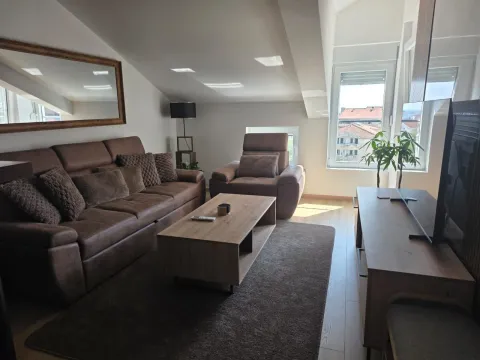 Living room with a brown sofa set, wooden coffee table, and television under a sloped ceiling. - image 11