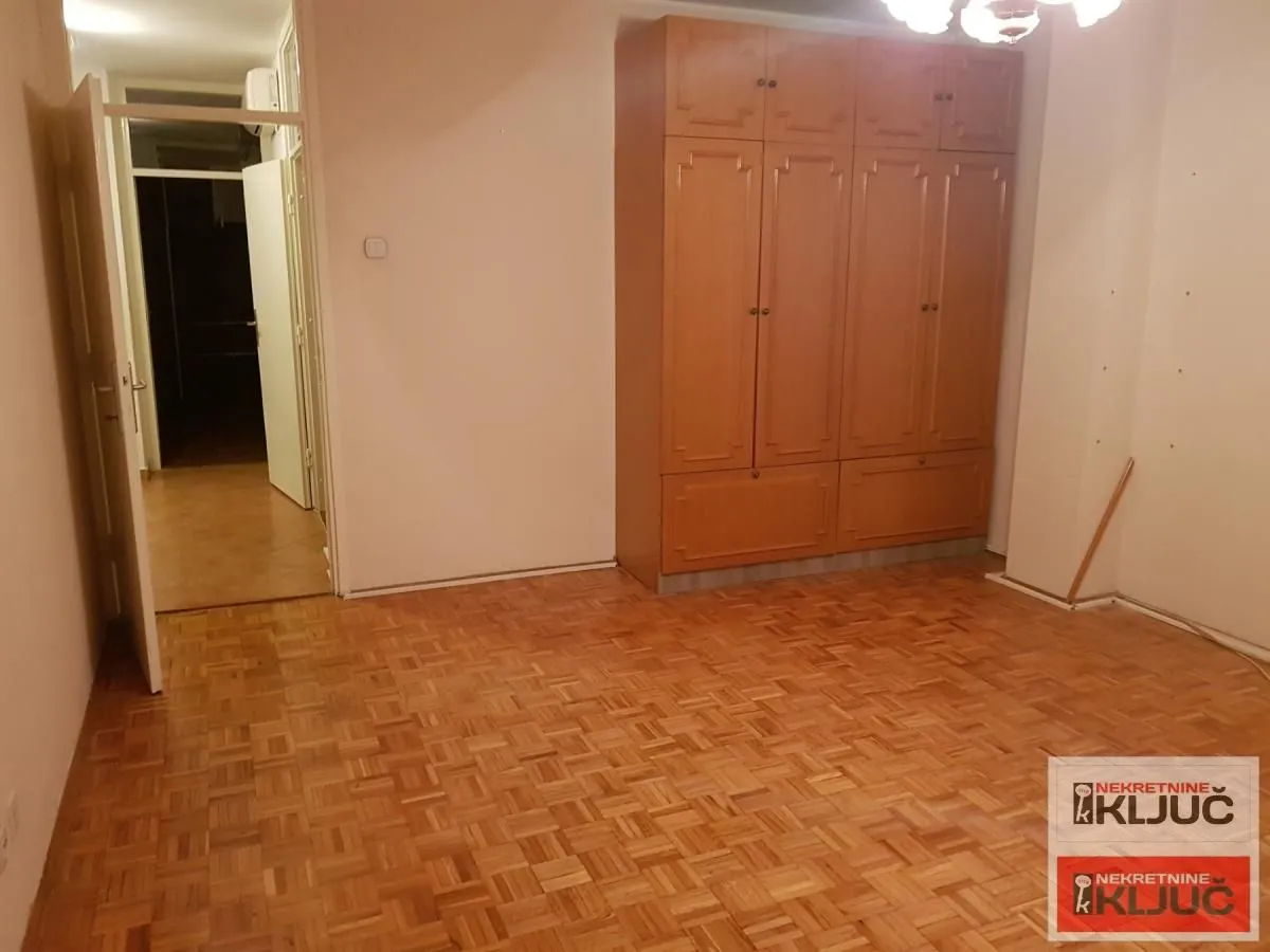 Prazna soba sa ugradnim ormanom i parketom na podu.