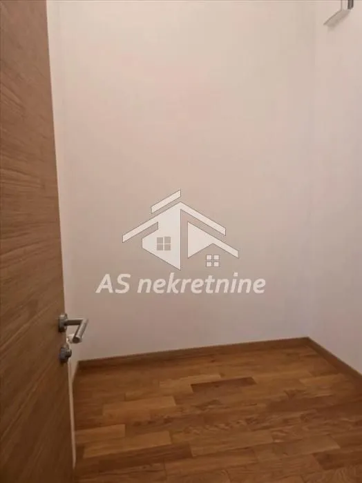 Empty room with wooden flooring and a door.