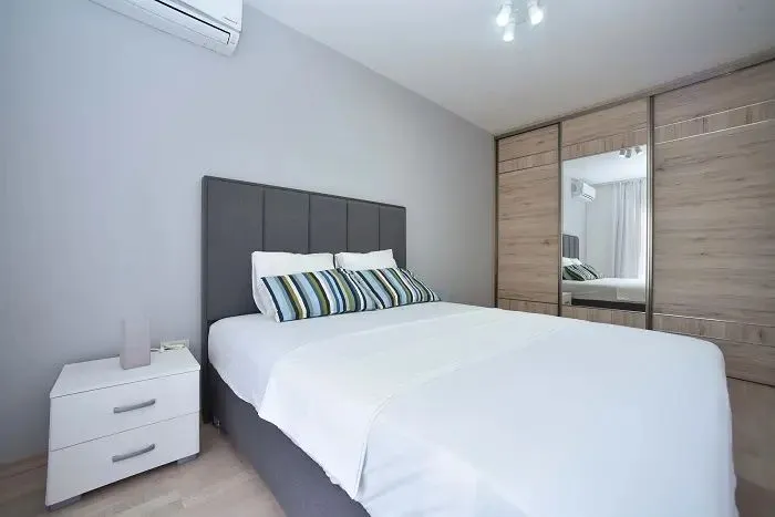 Bedroom with a double bed, nightstand, and built-in wardrobe with a mirror.