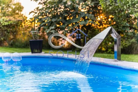 Swimming pool in the yard with a water cascade and surrounding greenery. - image 16