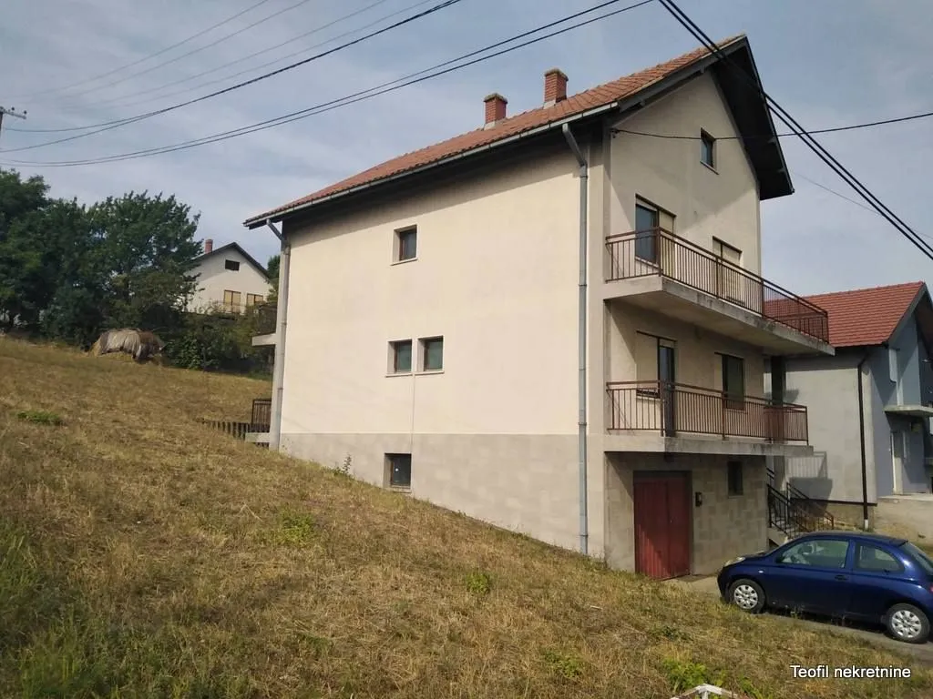 Pogled na spoljašnjost trospratne kuće sa terasama i travnatim dvorištem.