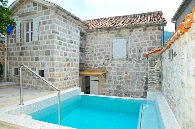 Eksterijer tradicionalne kamene kuće sa bazenom u dvorištu.