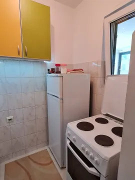 Small kitchen equipped with a stove, refrigerator, and wall cabinets. - image 6