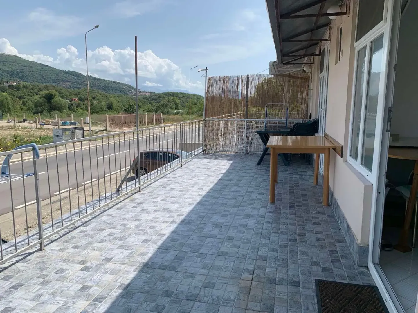 Prostrana popločana terasa sa pogledom na ulicu i okolinu.