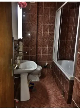 Kupatilo sa smeđim pločicama, kadom i lavaboom. - image 5