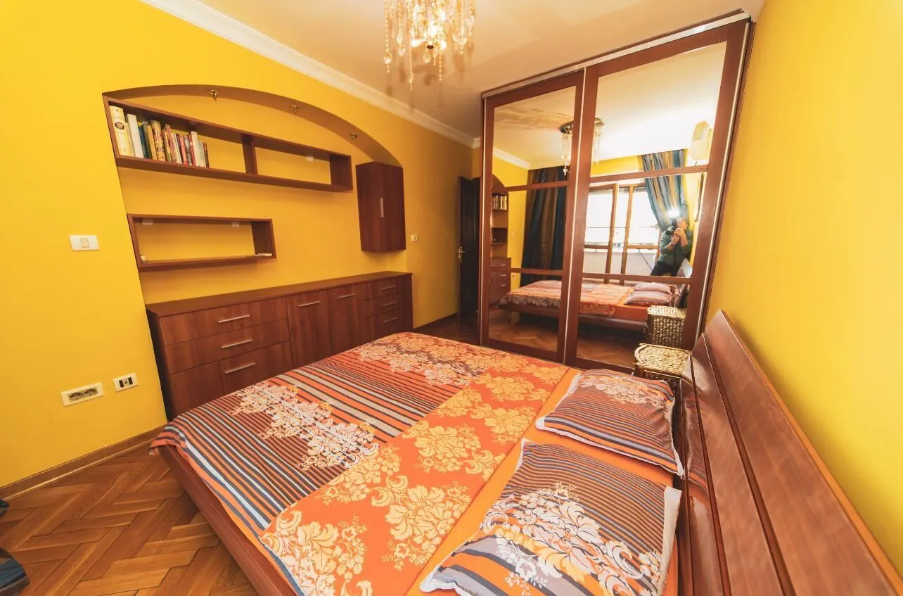 Furnished bedroom with a double bed, mirrored wardrobe and yellow walls.