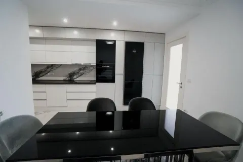 Kitchen equipped with white units and black built-in appliances, featuring a dining table. - image 10