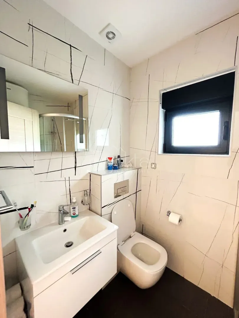 Moderno opremljeno kupatilo sa umivaonikom, WC šoljom i tuš kabinom.