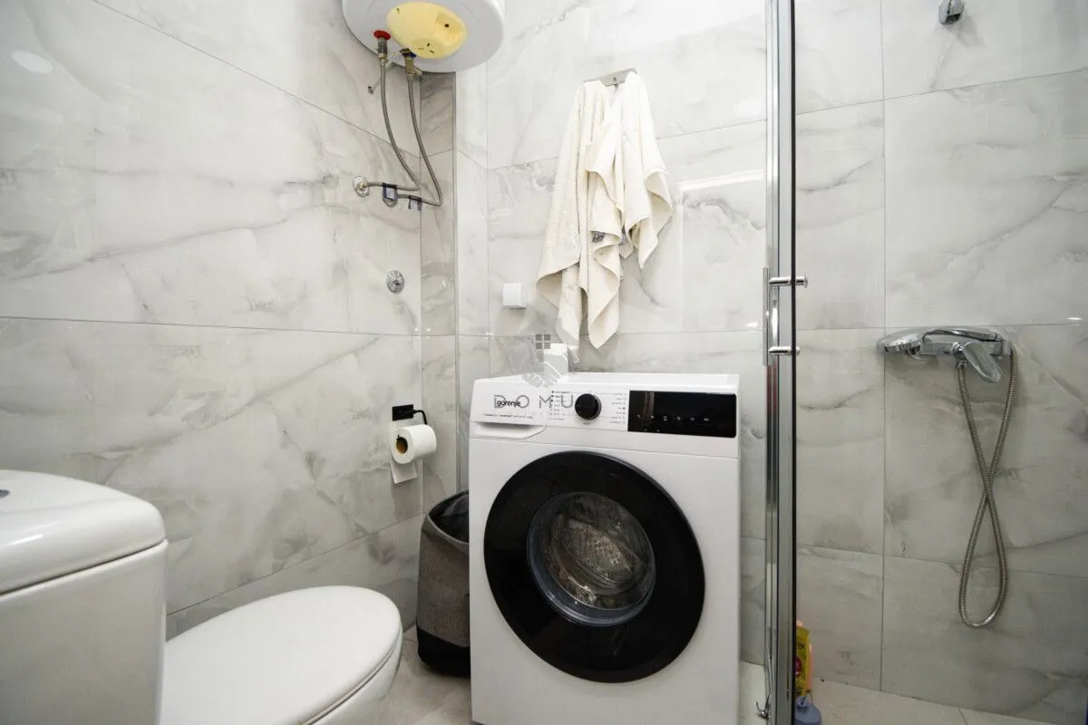 Kupatilo opremljeno tuš kabinom, WC šoljom i veš mašinom.