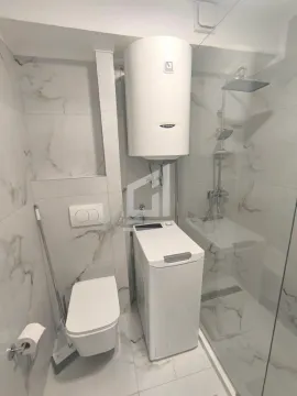 Bathroom equipped with a walk-in shower, toilet, water heater, and washing machine. - image 5