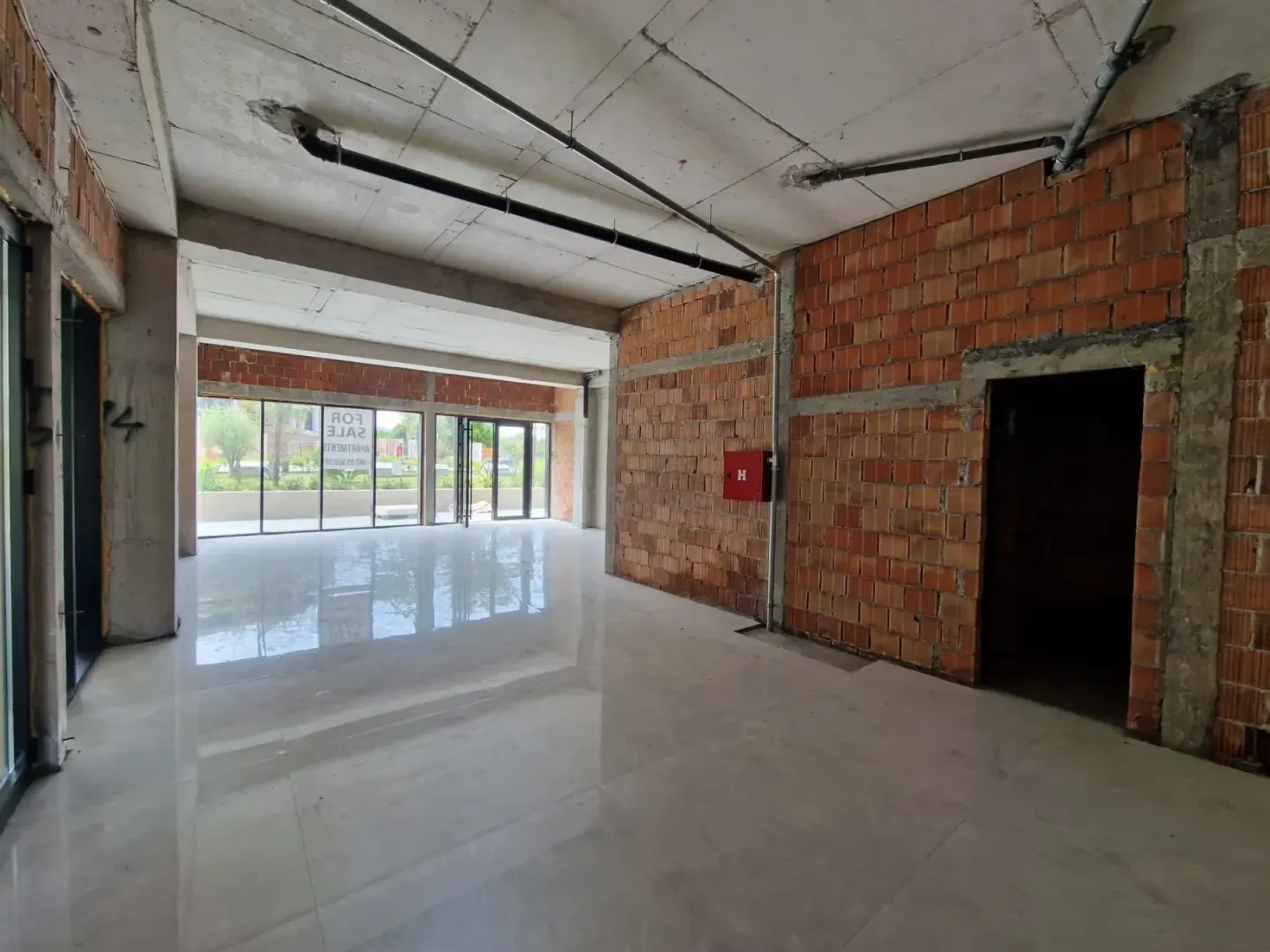 Unfinished space under construction with tiled floor and large glass surfaces.