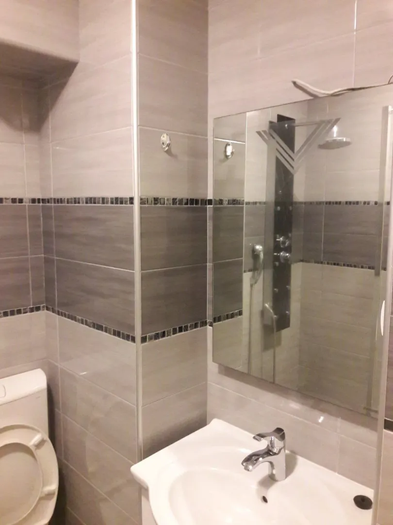 A bathroom featuring a washbasin, mirror, and toilet in light tones.
