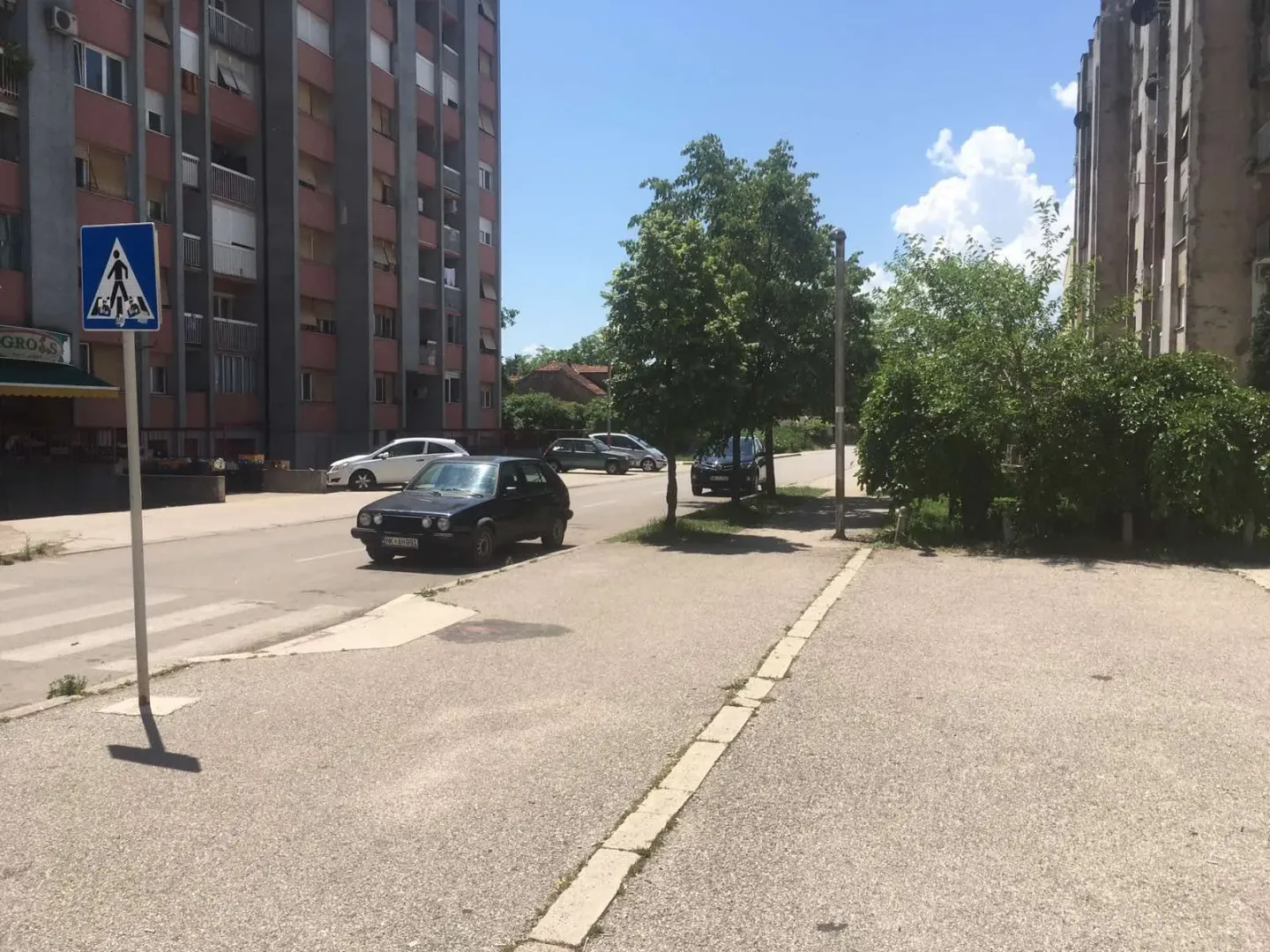 View of the street in front of the building with parking and trees.